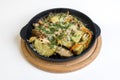 Dish on a black pan, which stands on a wooden stand. Baked potatoes with meat red and yellow pepper. Sprinkled with green parsley Royalty Free Stock Photo