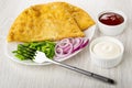 Dish with cheburek, chopped scallion, onion, fork, ketchup and mayonnaise on wooden table