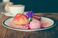 A dish of Choux cream , rose ice-cream and passion fruit with beautiful decoration and woman drinking coffee in background