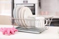 Dish drainer with clean dinnerware on table Royalty Free Stock Photo