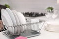 Dish drainer with clean dinnerware on table Royalty Free Stock Photo