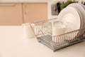 Dish drainer with clean dinnerware on table Royalty Free Stock Photo