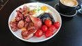 A dish of English full breakfast with a lot of sausage, eggs, tomatoes, and large piece of mushroom