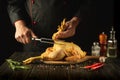 A dish of fried chicken by the hands of the chef in the kitchen of the restaurant. Preparing to cook a raw rooster on a cutting