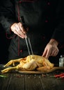 A dish of fried chicken by the hands of the chef in the kitchen of the restaurant. Preparing to cook a raw rooster on a cutting