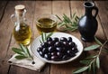 Dish full of black olives and glass decanter of extra virgin olive oil with branches stand on rural wooden table Royalty Free Stock Photo