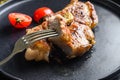 Dish of grilled pork chop with tomatoes top view with knife and slice on fork over old rustic dark wood table table close up new Royalty Free Stock Photo