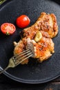 Dish of grilled pork chop with tomatoes top view with knife and slice on fork over old rustic dark wood table table close up top Royalty Free Stock Photo