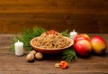 Dish with kutia - traditional Christmas treat of the Slavs on Christmas Eve. Fur-tree branch, apple, candle on a wooden background Royalty Free Stock Photo