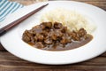 Dish of pieces of beef with onions and rice on a table