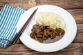 Dish of pieces of beef with onions and rice on a table