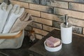 Dish with soap bars and bottle of shampoo on table near brick wall. Royalty Free Stock Photo