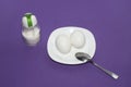 A dish of two eggs with a spoon and salt on a purple background. Royalty Free Stock Photo