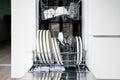 Dish washer machine. Washing plates and cutlery in basket. Open dishwasher in kitchen, front view. Full load of clean utensils. Royalty Free Stock Photo