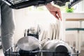 Dish washing machine. Washer in kitchen. Man using dishwasher and unloading clean plates and cutlery. Family housework. Royalty Free Stock Photo