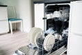 Dish washing machine. Washer in kitchen. Open dishwasher in modern white home. Full of clean plates. Royalty Free Stock Photo
