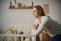 disheartened woman standing near crib with