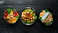 Dishes of chicken meat and vegetables in a black plate on a black background. Buddha bowl. Top view.