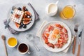 Dishes for home cooked hearty Breakfast. Fried eggs with sausages and tomatoes. Belgian fluted waffles with figs and grapes. Gray Royalty Free Stock Photo