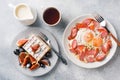 Dishes for home cooked hearty Breakfast. Fried eggs with sausages and tomatoes. Belgian fluted waffles with figs and grapes. Gray Royalty Free Stock Photo