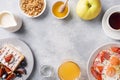 Dishes for home cooked hearty Breakfast. Fried eggs with sausages and tomatoes. Belgian fluted waffles with figs and grapes. Gray Royalty Free Stock Photo