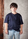 Disheveled and Dirty Caucasian Boy in Jeans and Blue T-Shirt Standing In Front of Stucco Wall Royalty Free Stock Photo