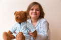 Disheveled little girl holding her pyjama-clad teddy bear