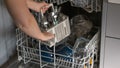 Dishwasher with clean dishes.Dishwasher disassembly.Womens hands sort clean dishes from the dishwasher. Plates, forks Royalty Free Stock Photo