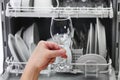 Open dishwasher, man hand taking out clean wine glass, after washing