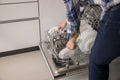 Dishwasher open and a woman removing the washed dishes. Royalty Free Stock Photo