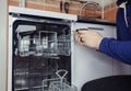 Dishwasher repair. A service center representative diagnoses and repairs a dishwashing machine at home. Specialist in working with Royalty Free Stock Photo