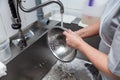 Dishwasher in uniform washes griddle with foam and sponge under the tap water Royalty Free Stock Photo