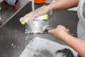 Dishwasher in uniform washes griddle with foam and sponge under the tap water Royalty Free Stock Photo