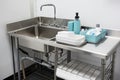 dishwashing station with industrial sink and drainage, roll-up drying rack, and sanitizer spray bottle