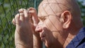 Disillusioned Man Image Looking Sad Thru a Metallic Fence Royalty Free Stock Photo