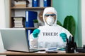 Disinfection man with special white suite working on laptop