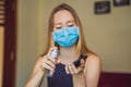 Disinfection of the phone. A woman in a medical mask holds a telephone and a spray disinfector in her hands. protection