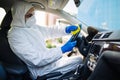 Disinfection professional cleans up a steering wheel of a car with a yellow rug. Sanitary service worker disinfects the vehicle`s