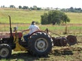 Disking a clover field on a hot summer`s day. A female farmer on a red and yellow tractor disking the field Royalty Free Stock Photo