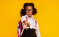 Displeased Black Schoolgirl Gesturing Thumbs-Down Disapproving Something Over Yellow Background