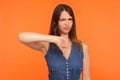 Dislike! Naughty dissatisfied brunette woman in denim dress frowning angrily and showing thumbs down Royalty Free Stock Photo