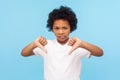 Dislike! Portrait of dissatisfied upset little boy with curly hair showing thumbs down gesture and looking displeased Royalty Free Stock Photo