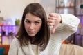 Upset young woman showing thumbs down, dislike bad work, disapproval, dissatisfied feedback at home Royalty Free Stock Photo