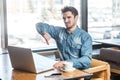 Dislike! Side view portrait of negative critique bearded young freelancer in blue jeans shirt are sitting in cafe and making video