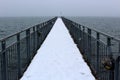 Dismal snowy day with metal wharf reaching out over choppy waters