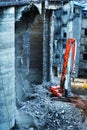 Dismantling a dilapidated building using heavy equipment. Reinforced concrete cutting with hydraulic scissors. Vertical photo