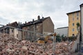 Dismantling an old building in the old city with an excavator. A pile of broken bricks and rebar in the foreground Royalty Free Stock Photo