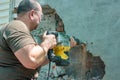 Dismantling walls and openings with an electric jackhammer. The worker in goggles performs repair work