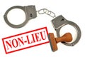 Dismissal written in french on white background next to an ink pad and handcuffs