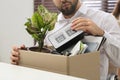 Dismissed man packing personal stuff into box in office, closeup Royalty Free Stock Photo